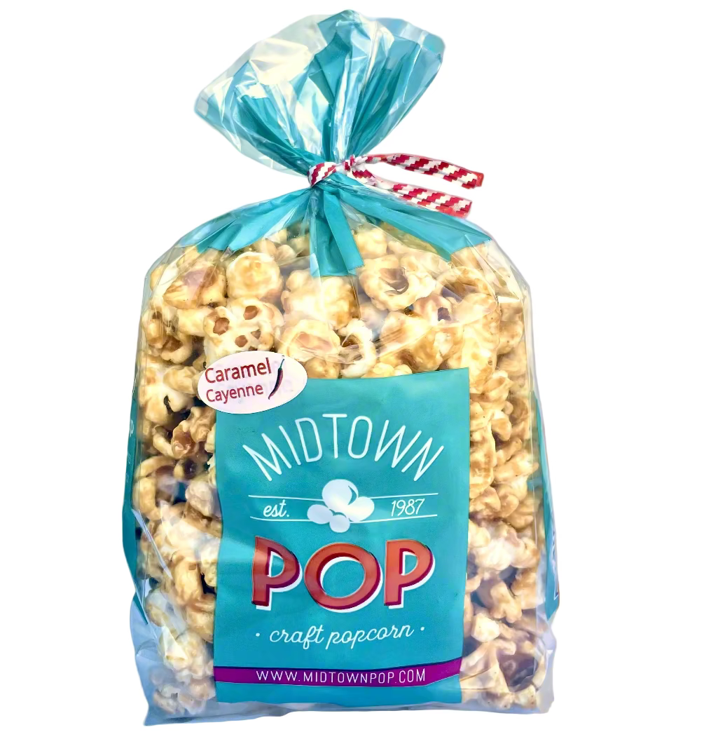 A clear plastic bag filled with caramel popcorn The label on the front reads 'Midtown POP craft popcorn' with a smaller text 'Caramel Cayenne' and a website address.