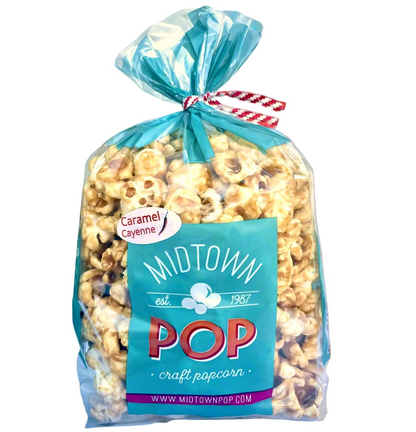 A clear plastic bag filled with caramel popcorn The label on the front reads 'Midtown POP craft popcorn' with a smaller text 'Caramel Cayenne' and a website address.